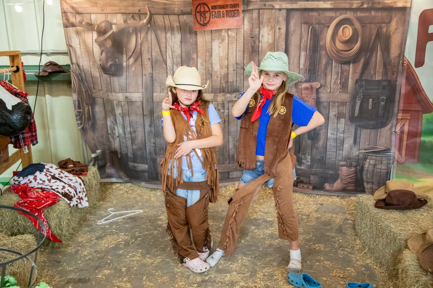 Two girls posing in cowboy vests and hats at the photo booth