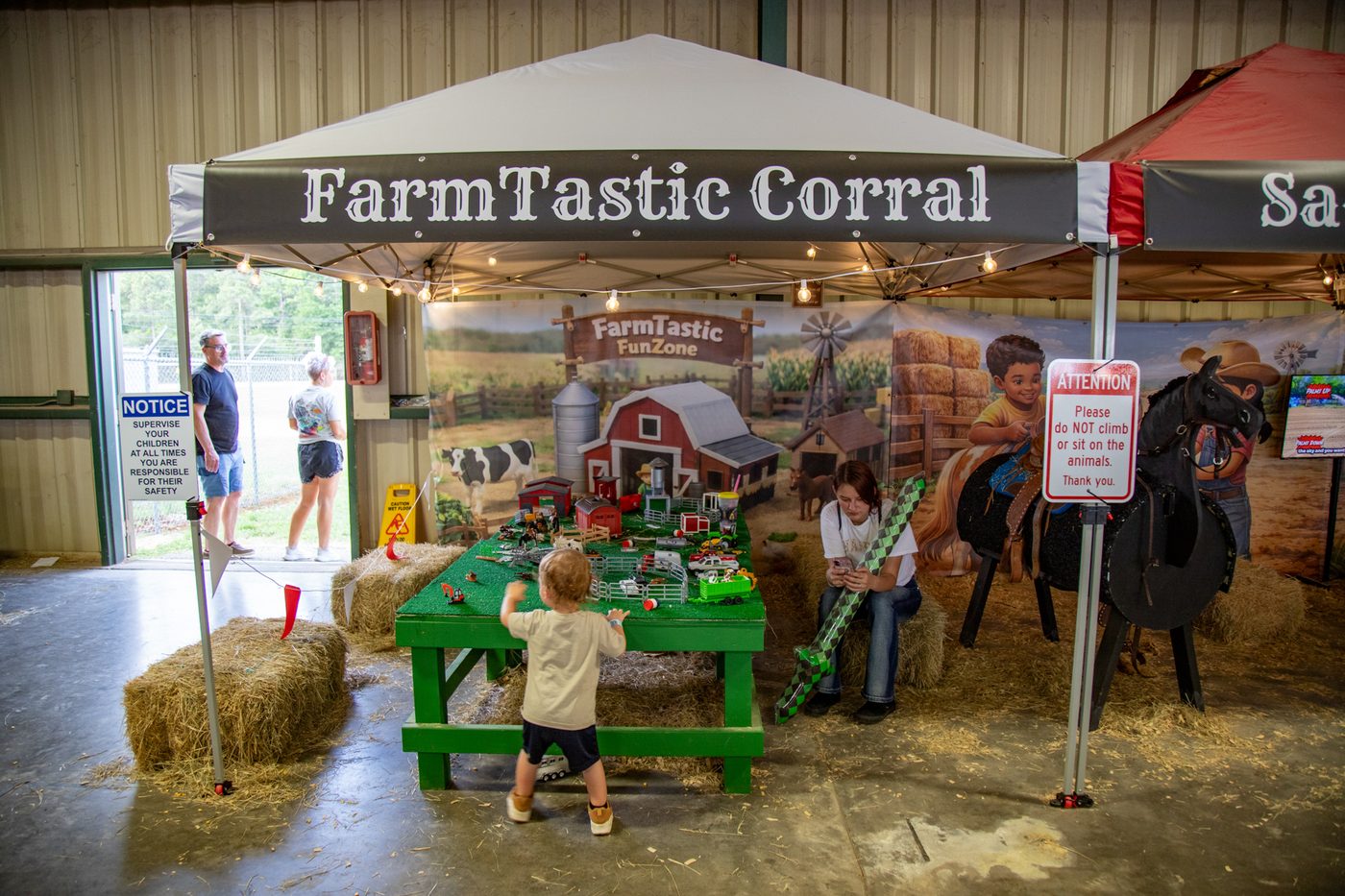A toddler playing at the FarmTastic Corral toy barn table