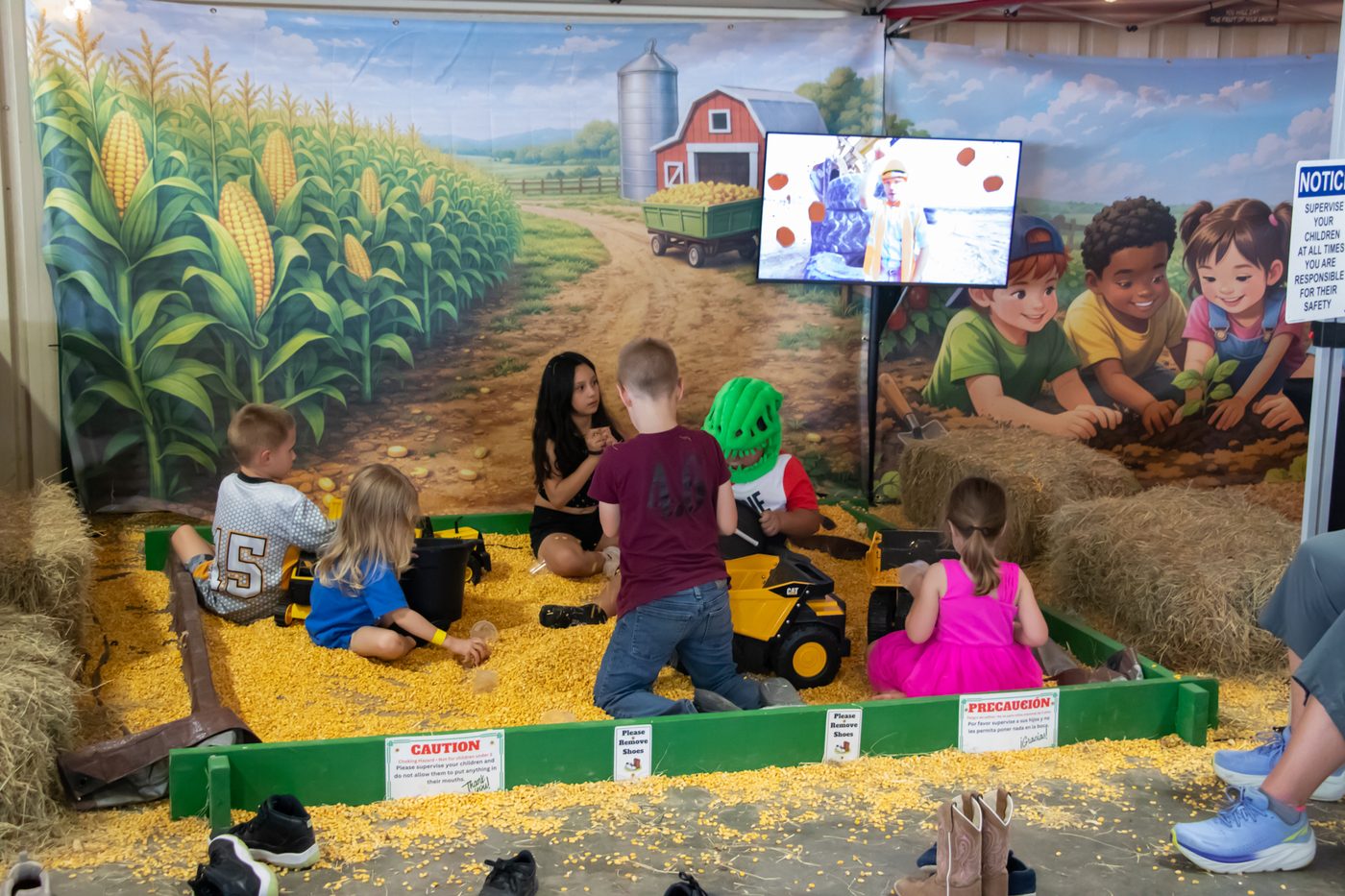 Kids playing together in the corn kernel pit with toy dump trucks