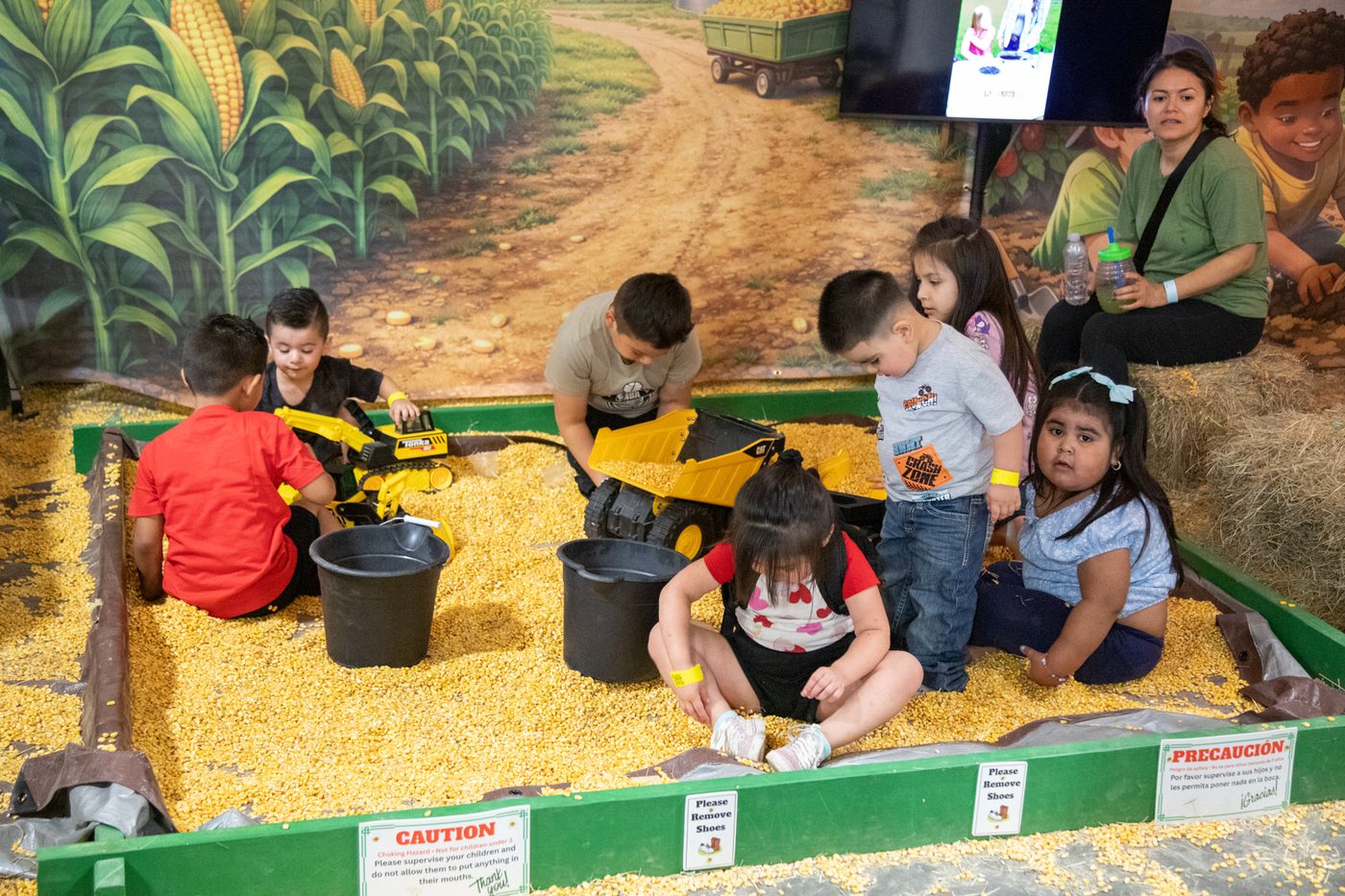A child scooping corn kernels with a toy excavator