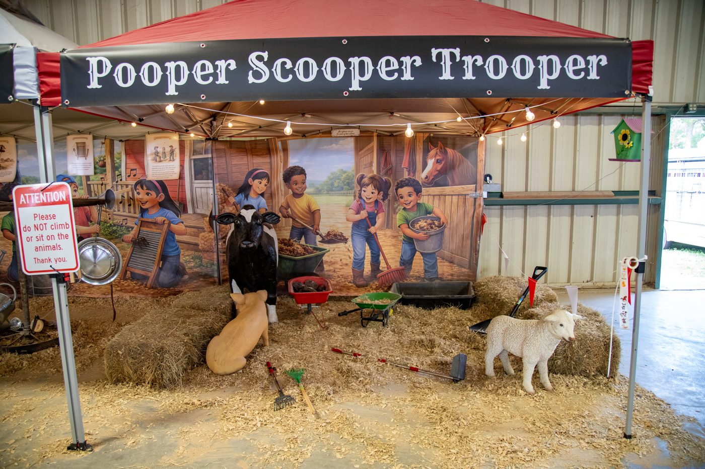 The Pooper Scooper Trooper booth, with toy farm animals, wheelbarrows, and cleaning tools
